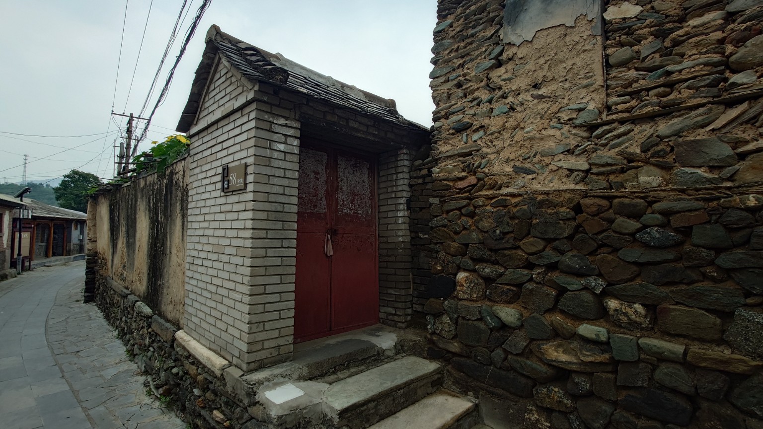 A narrow Nanjiao alley where newer brickwork meets an older stone and earth wall