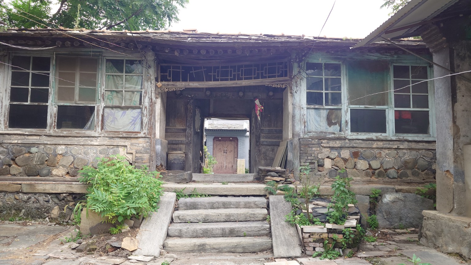 A weathered Nanjiao courtyard with pale green windows and carved timber details