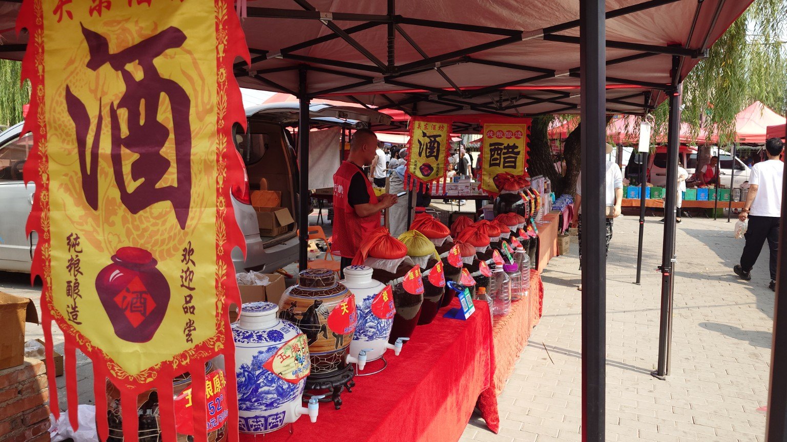 Rows of ceramic baijiu urns with taps beneath yellow liquor and vinegar banners at Shahe Daji