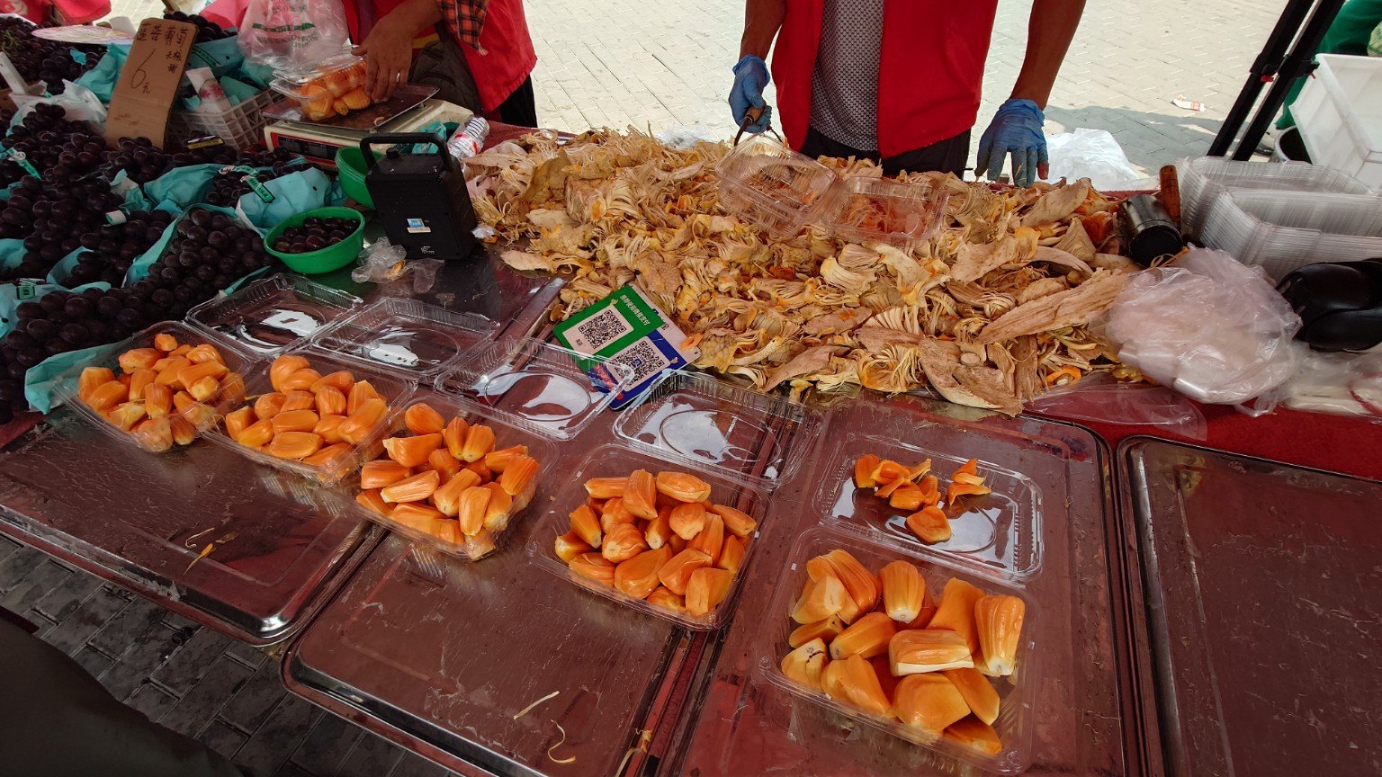 Freshly opened jackfruit piled behind trays of golden fruit as vendors cut and pack it