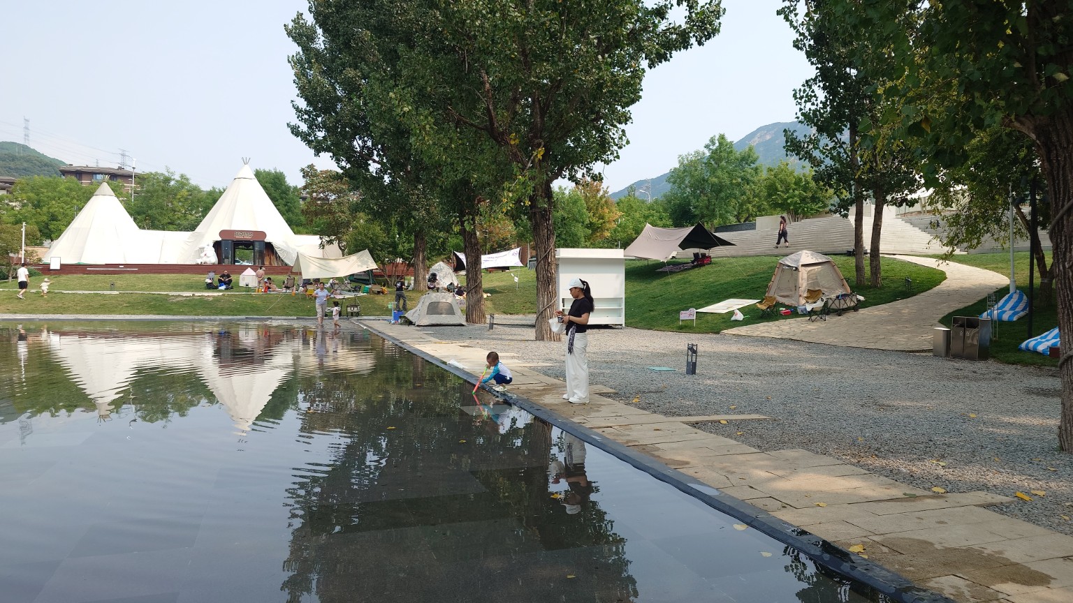 Families camping and playing beside a shallow pool in Tanzhesi
