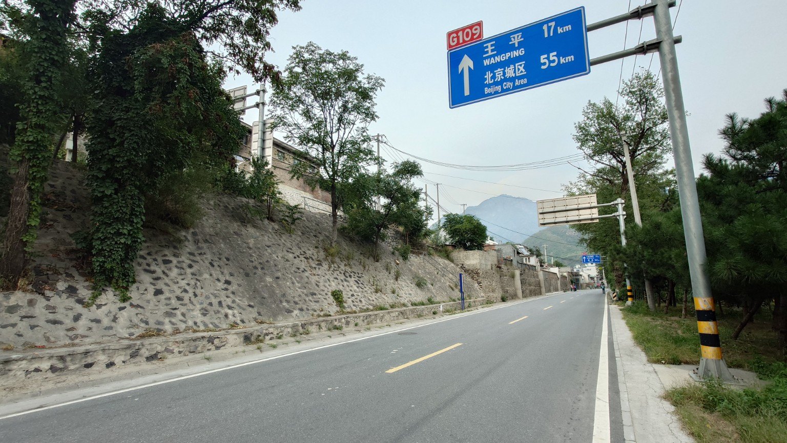 National Highway G109 through Yanchi beneath a sign reading Beijing City Area 55 km and Wangping 17 km