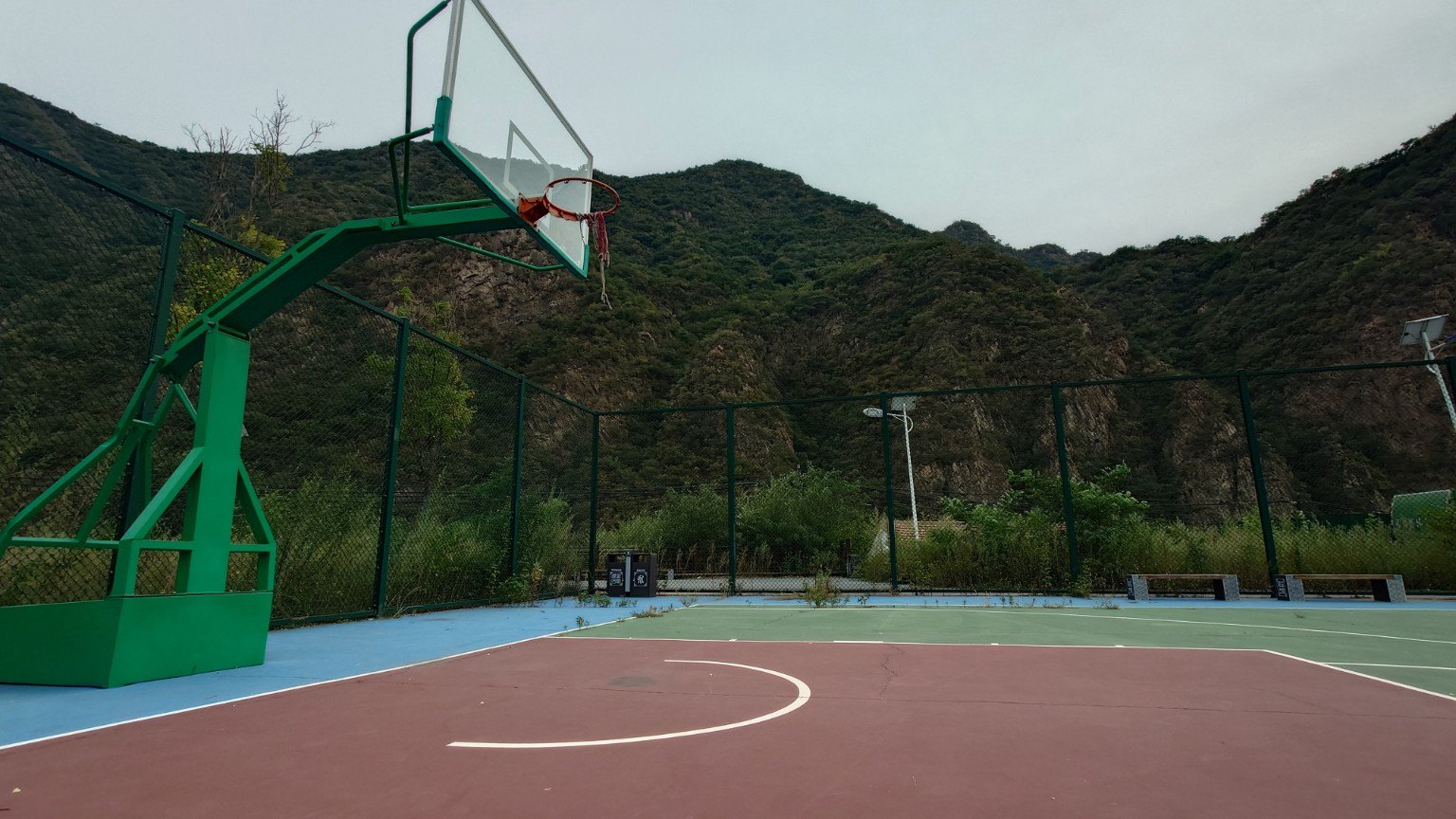 An outdoor basketball court framed by steep rocky mountains and vegetation in Yanchi