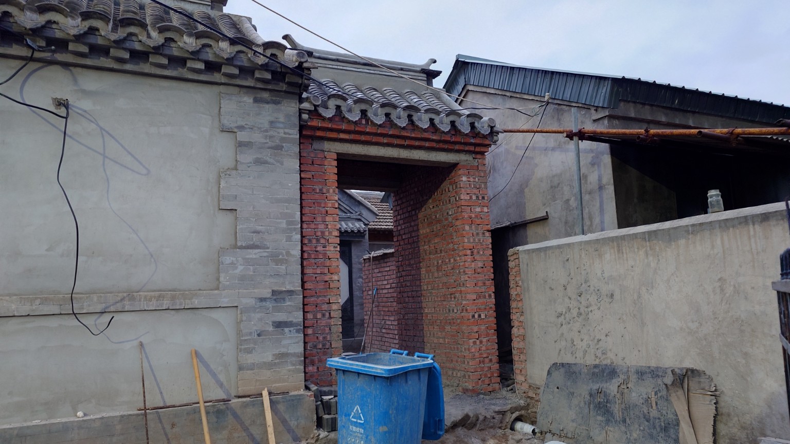 A traditional courtyard entrance under active brick and utility renovation in Lingshui
