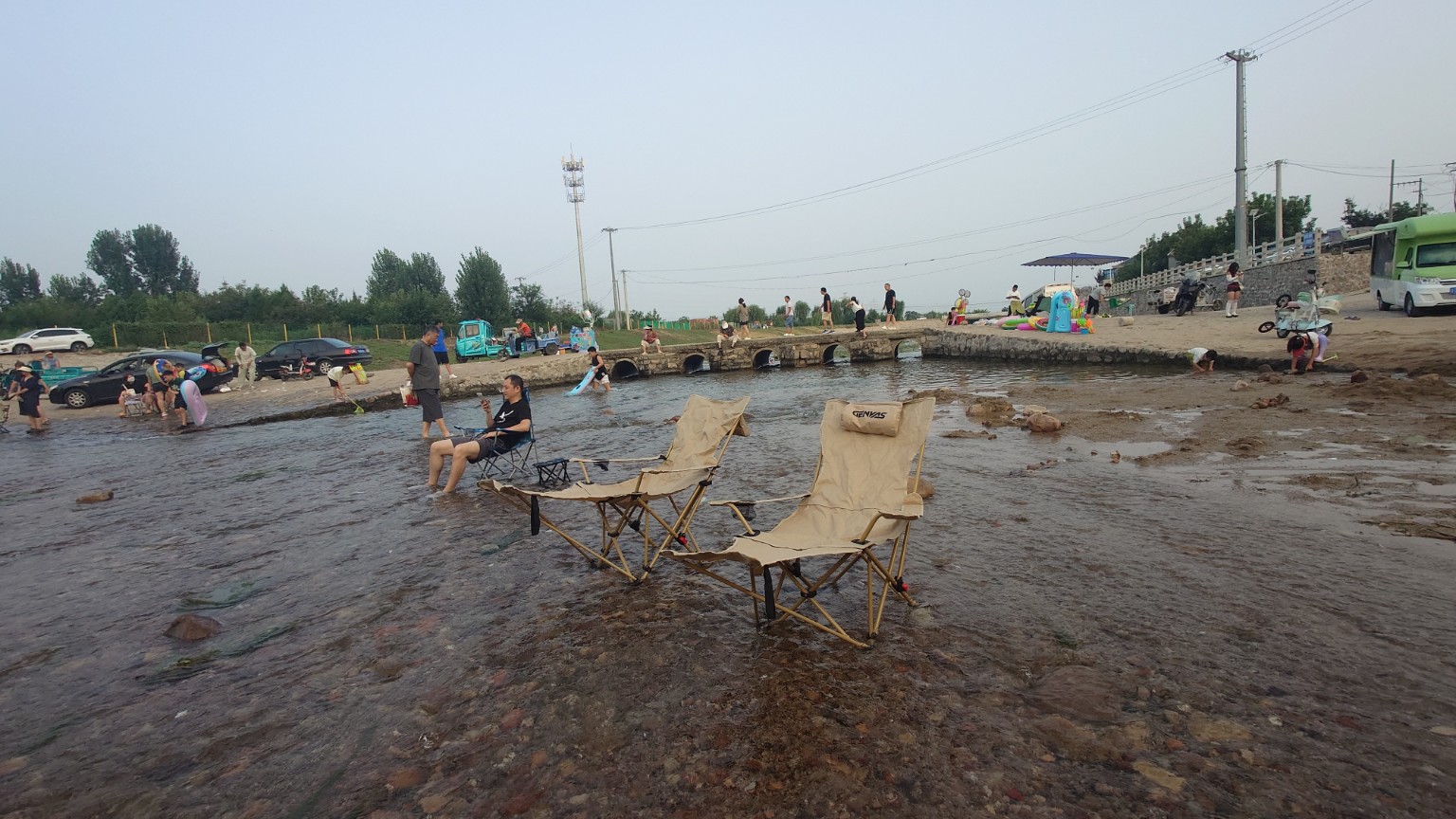 Folding chairs and families enjoying a shallow river recreation area in Pinggu