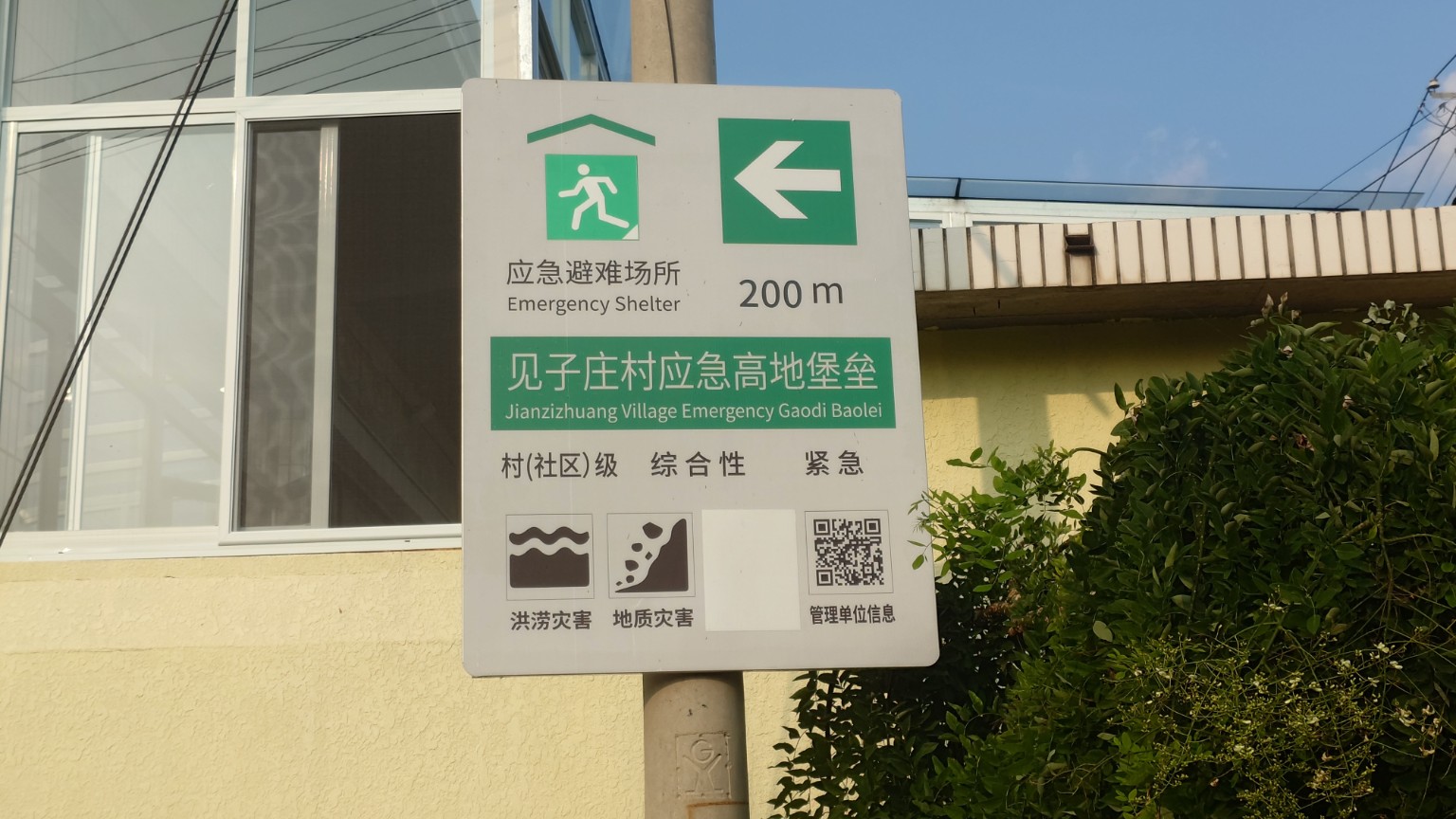 A bilingual sign pointing to the Jianzi Village high-ground emergency shelter