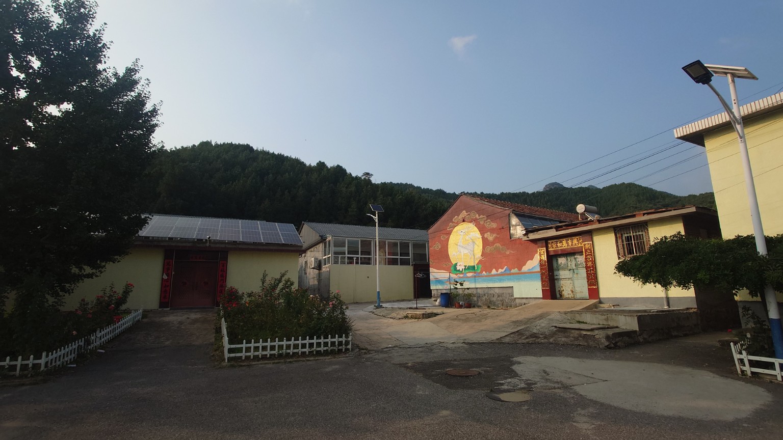 Village courtyard homes with solar panels and a mountain ridge behind them
